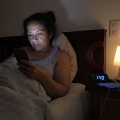 Mujer despierta en la cama a la 1:40 de la mañana mirando el celular